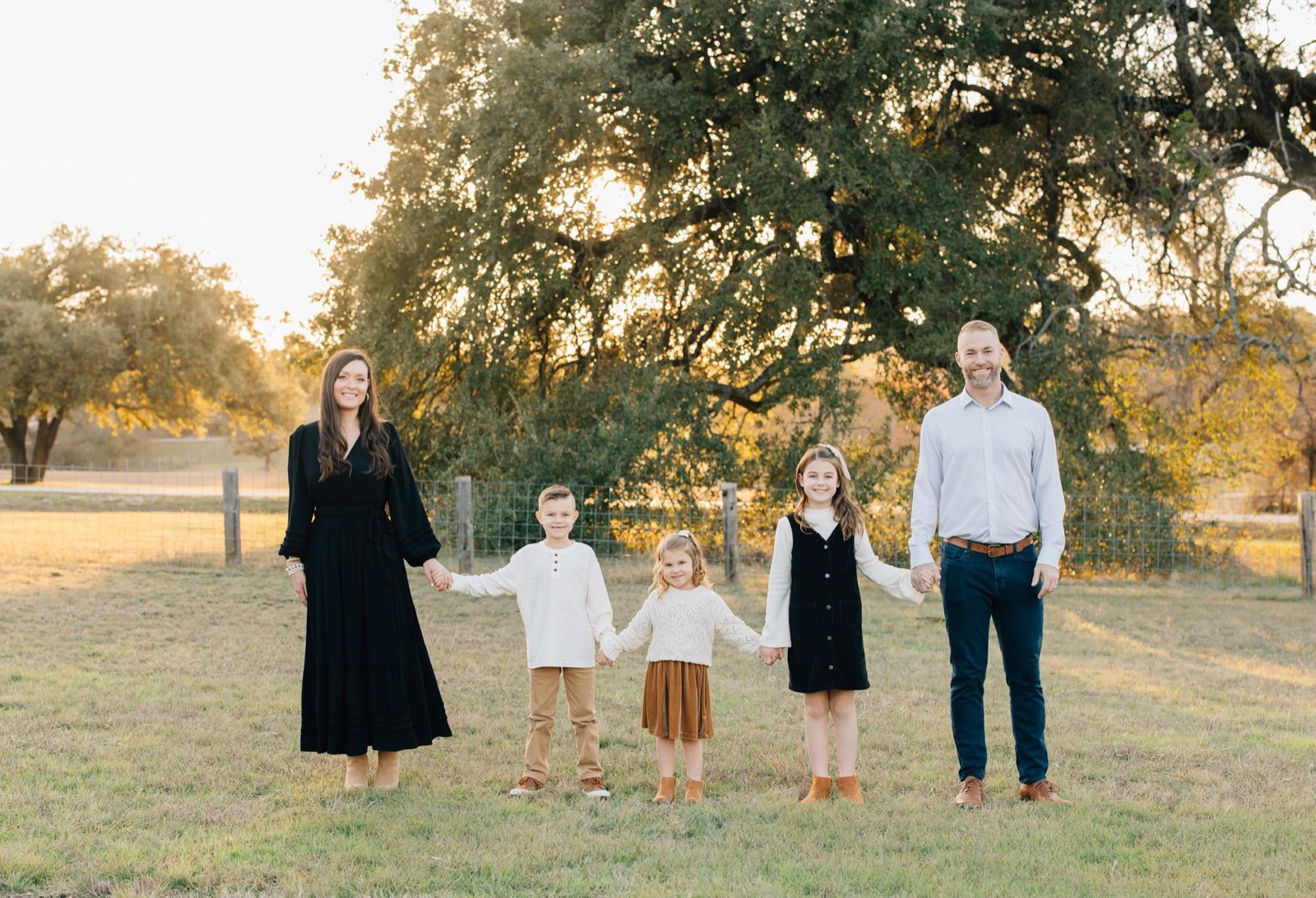 Sarah and her family holding hands together outdoors at golden hour